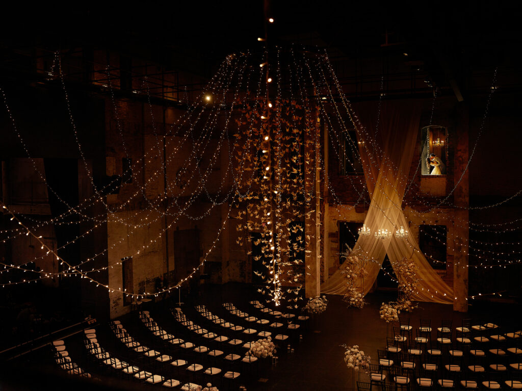 twinkling string of lights hanging from above with a wedded couple kissing on the right side at Aria