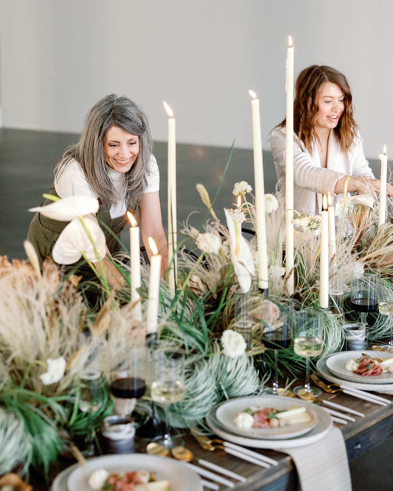 two smiling wedding designers and planners creating a gorgeous natural grass tablescape