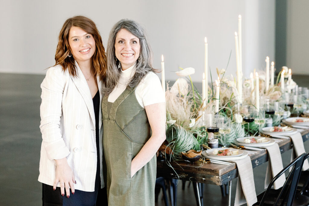 two smiling wedding planners pictured near their tablescape design